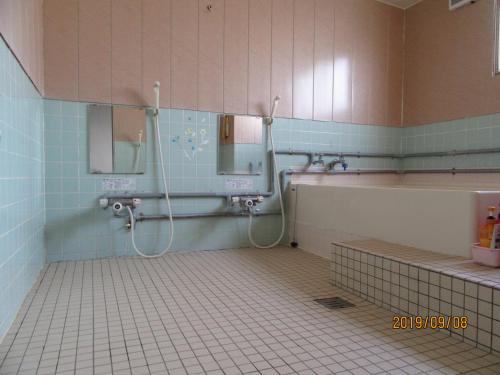 a bathroom with a shower and a tub and a sink at Minshuku Mutsukari in Furano