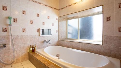 a bathroom with a tub and a window and a television at LCO-Resort in Takizawa