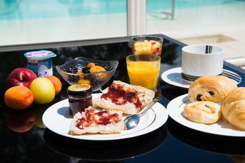 un tavolo con due piatti di prodotti per la colazione e bevande di Citotel Hôtel Le Capricorne a Marmande