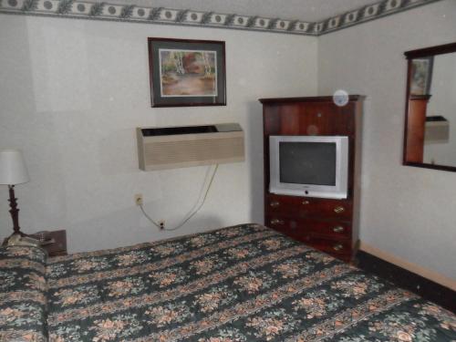 a hotel room with a bed and a tv at Red Carpet Inn Brooklawn in Brooklawn