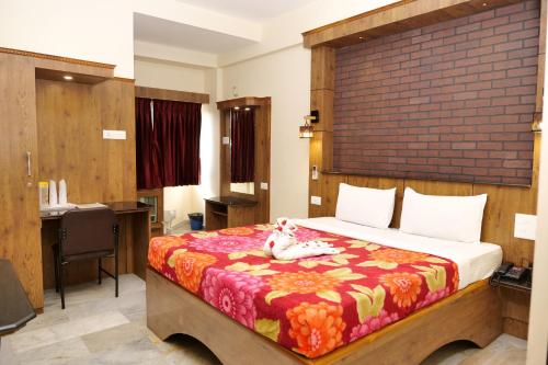 a bedroom with a bed and a desk with a desk at Sakthi Hotel in Pollāchi