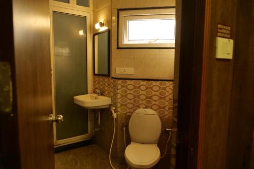 a bathroom with a toilet and a sink at Sakthi Hotel in Pollāchi