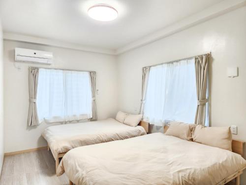two beds in a room with two windows at seragaki blue twins 201 in Onna