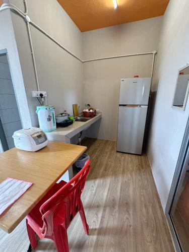 a kitchen with a wooden table and a refrigerator at Baby Devil Studio 8 pax Homestay in Sibu