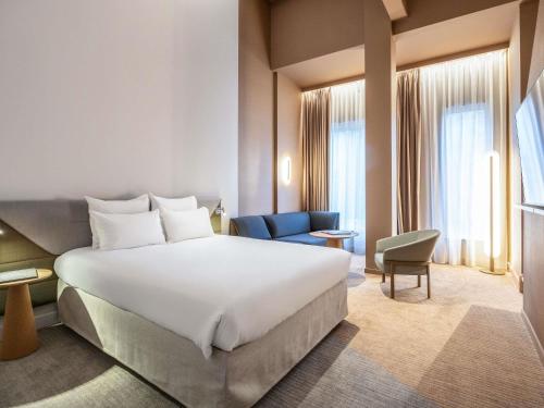 a hotel room with a large bed and a chair at Novotel Brugge Centrum in Bruges