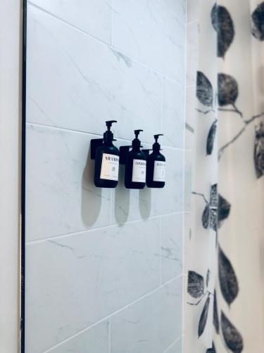 a bathroom with three bottles of soap on a wall at Chic City Escape- come experience tranquility! in Calgary