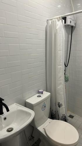 a white bathroom with a toilet and a sink at Kyle's Bed and Breakfast DMall Boracay in Boracay