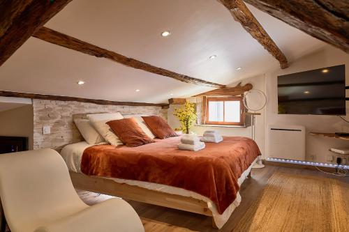 a bedroom with a large bed and a chair at Loft Unique Romantique & Balnéothérapie in Riom
