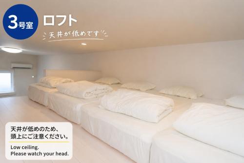 Drei Betten mit weißen Kissen in einem Zimmer. in der Unterkunft Green Field in Sasebo