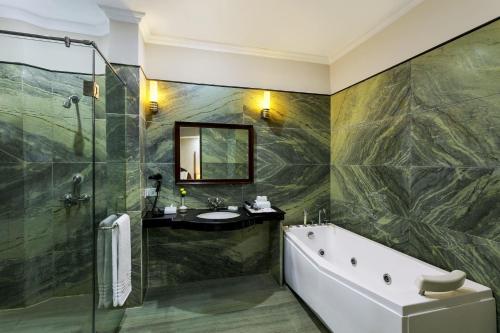 a bathroom with a tub and a sink and a mirror at Ramada Khajuraho in Khajurāho