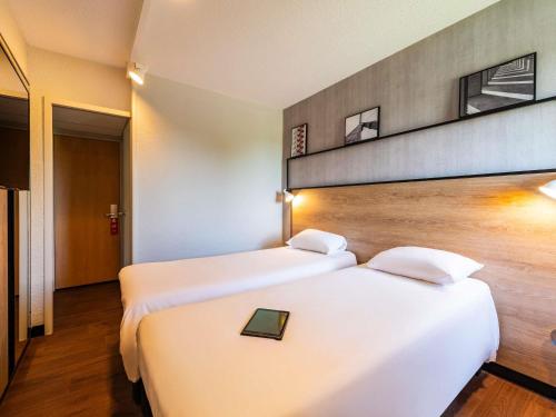 two beds in a hotel room with a tray on top at ibis Besançon Marchaux in Marchaux