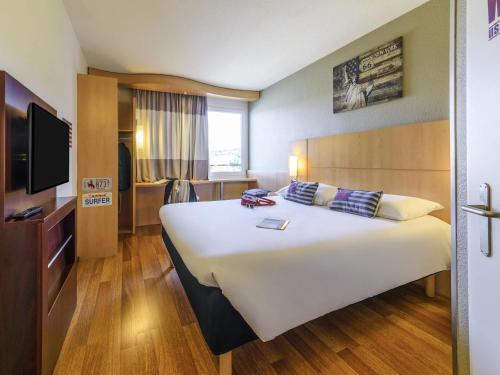 a hotel room with a large bed and a tv at ibis Lausanne Crissier in Lausanne