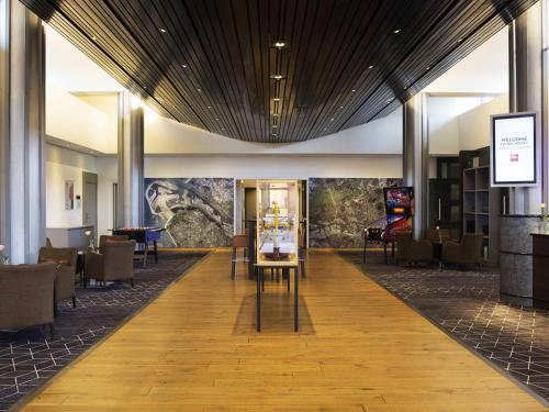 a lobby of a hotel with tables and chairs at ibis Rotterdam Vlaardingen in Vlaardingen