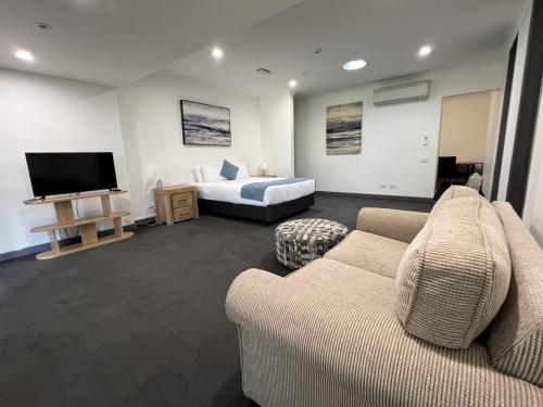 a living room with a couch and a bed and a television at Invercauld House in Goonellabah