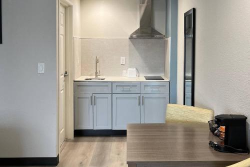 a kitchen with white cabinets and a table and a sink at Quality Inn Tracy I-205 in Tracy