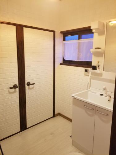 a bathroom with a door and a sink and a window at 아라무사aramoosa민숙 in Tsushima