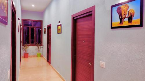 a hallway with two red doors in a building at Asapian Vanyamahal - A Nature Resort in Rāmnagar