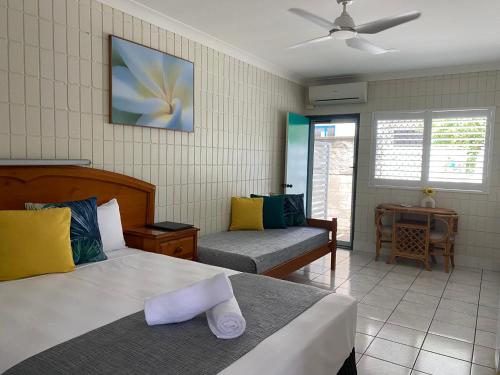 a bedroom with two beds and a couch at Tropical Palms Resort & 4WD Hire in Picnic Bay