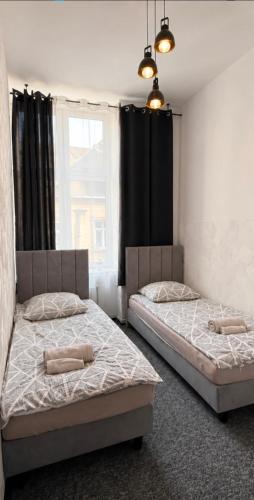 two beds in a bedroom with a window at Apartament X in Przemyśl