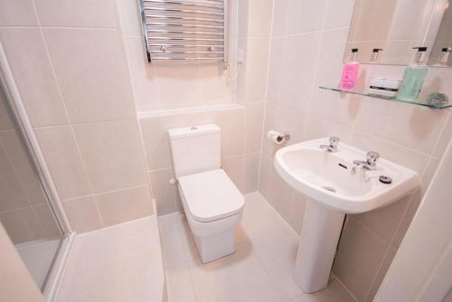 a white bathroom with a toilet and a sink at The Burley Inn in Burley
