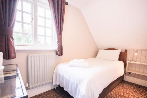 a bedroom with a white bed and a window at The Burley Inn in Burley