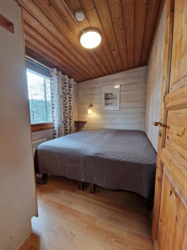 a bedroom with a bed in a wooden room at Rantamökki 28 in Syöte