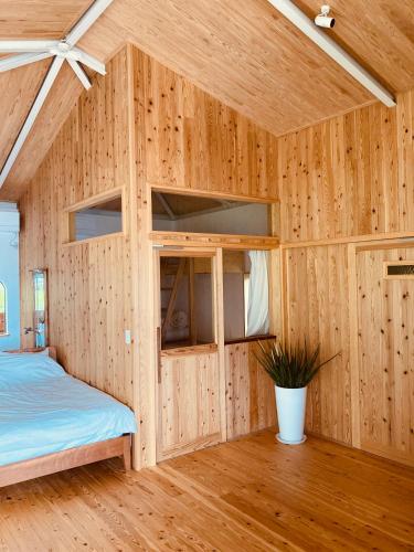 a bedroom with a bed in a wooden wall at 丘の上の小さなスローリゾート フェニックスの宿 in Miyazaki