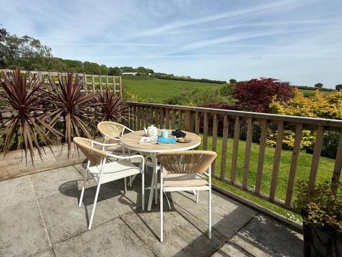 a table and chairs on a balcony with a view at The Burrow Devon in Longdown