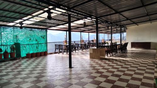 a restaurant with tables and chairs in a large room at Hotel Skyline in Kanatal