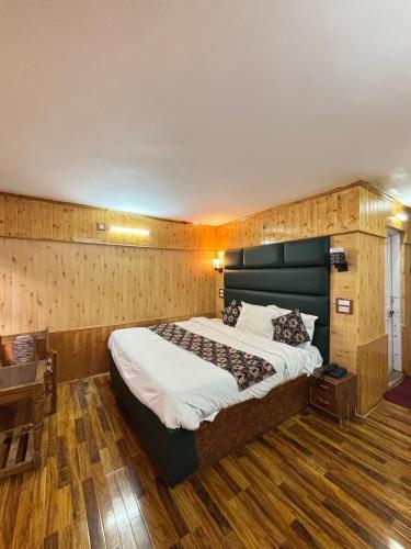 a bedroom with a large bed and wooden floors at Hotel king palace in Pahalgām