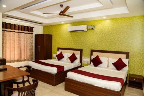 a hotel room with two beds and a table and a desk at Hotel Grand In Near 2 Min From Vaishali Metro Station in Ghaziabad