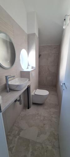 a bathroom with a sink and a toilet and a mirror at Apartments BEVANDA in Šimuni