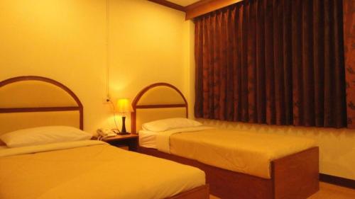 a hotel room with two beds and a window at Supak Hotel in Kalasin