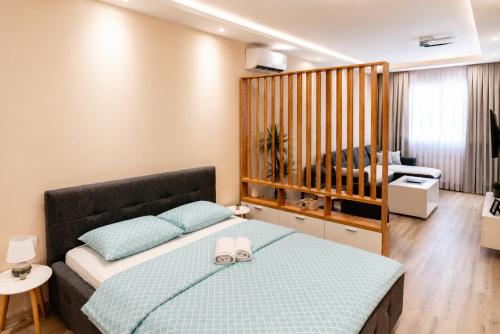a bedroom with a bed and a living room at Apartman Harmony in Prijedor