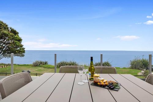 a table with two glasses and a bottle of wine at Beachfront Breeze - sea views for days in New Plymouth