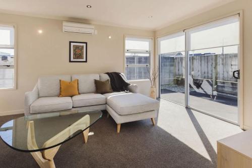 a living room with a couch and a glass table at Sail-Shaped Townhouse in New Plymouth in New Plymouth