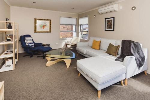 a living room with a couch and a glass table at Sail-Shaped Townhouse in New Plymouth in New Plymouth
