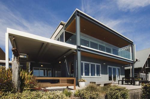 a house with a bench in front of it at Clifftops - oceanfront retreat in Oakura Beach in Oakura