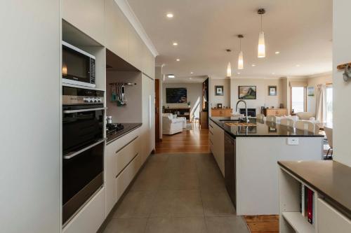 a kitchen with black appliances and a living room at Clifftops - oceanfront retreat in Oakura Beach in Oakura