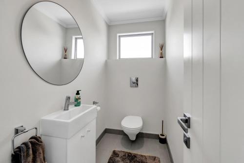 a white bathroom with a sink and a mirror at Executive On Parkview - 3BR modern family home in New Plymouth