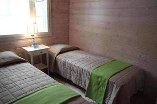 a bedroom with two beds and a table with a lamp at Villa Lotta in Virttaa