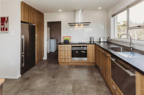 a kitchen with wooden cabinets and a sink at Love It On Lemon - modern townhouse near CBD in New Plymouth