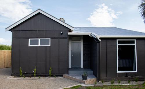 a black house with a garage at The Window Seat - pet-friendly 1BR apartment in Waitara