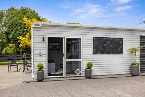 a small white shed with two potted plants at Naki Nook - Accommodation Stratford in Stratford