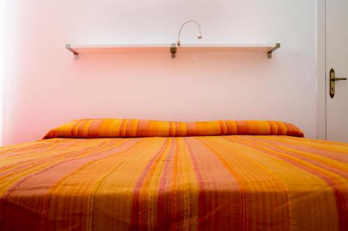 a bed with an orange and yellow striped blanket at B&B Dimora San Vincenzo in Gallipoli