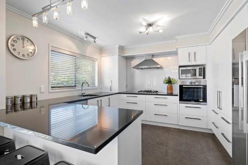 a kitchen with white cabinets and a clock on the wall at Seven By The Sea - stylish apartment near port in New Plymouth
