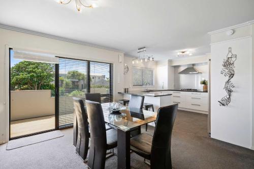 a dining room and kitchen with a table and chairs at Seven By The Sea - stylish apartment near port in New Plymouth