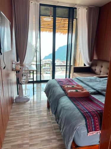 a bedroom with a bed and a large window at ผาฮี้แลนด์โฮมสเตย์ in Mae Sai