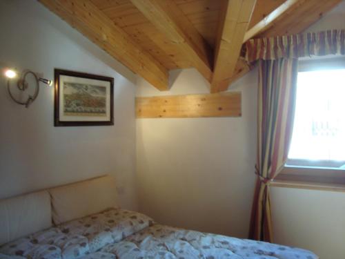 Schlafzimmer mit einem Bett und einem Fenster in der Unterkunft Fantastic Penthouse in Canazei in Canazei