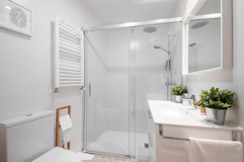 a white bathroom with a shower and a sink at Glory Suite Zurriola Beach with AC in San Sebastián